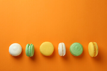 Concept of tasty dessert with macarons on orange background