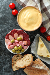 Concept of delicious food with fondue on black smokey table