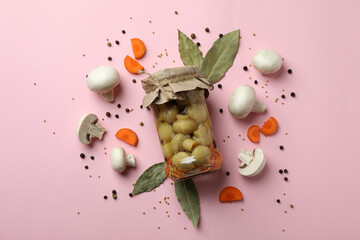 Jar with marinated mushrooms on pink background