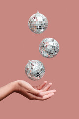 disco ball floating in the air under hand against beige background 
