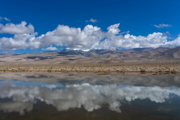 Scenic high altitude mountain landscape with blue sky and clouds reflection in water near Karakul...