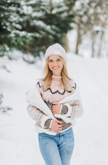 Beautiful woman posing near snow-covered Christmas trees in winter park.