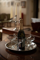 A tray with glasses of champagne and a bottle of sparkling wine.