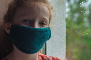 Young Girl Wearing a Homemade Mask and Looking Sad While in Lockdown due to Covid-19.