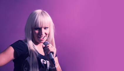 Blond woman sing with mic in karaoke on pink background with a lot of copyspace.