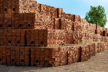 Pallets with red bricks on industrial site.