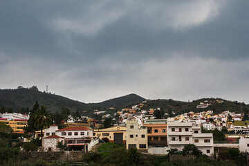 Fototapeta na wymiar Scenic view on volcanic mountain valley and typical house facades of historical town Teror in Gran Canaria (Province of Las Palmas, Canary Islands, Spain). Moody panoramic countryside landscape.