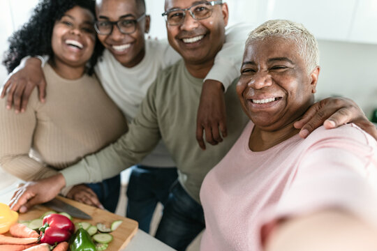 Happy Latin family taking selfie while preparing healthy lunch in modern kitchen at home - Food and parents unity concept