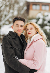 Fototapeta premium Handsome man and his lovely bride pose on the snow in a magic winter forest