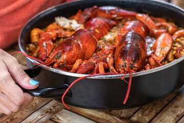 Woman taking Spanish paella with lobster. Close up
