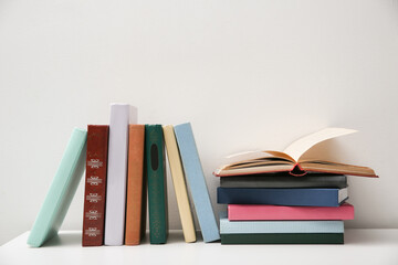 Different books on white table near light grey wall