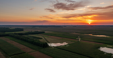 Naklejka na ściany i meble Colorful sunset over forest and fields aerial
