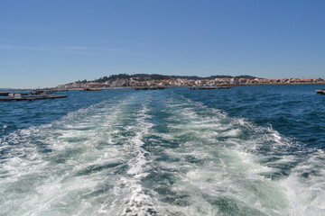 Route du bateau: direction laissant vagues et écumes. Sur fond de ville et d'élevage de moules