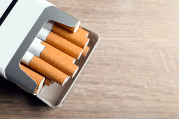 Cigarettes in pack on wooden table, top view. Space for text