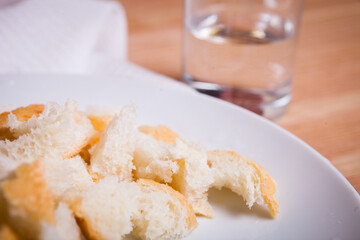 Croutons on a white plate and a glass of water nearby.