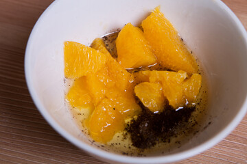 Cooking Ingredients: Orange slices in oil with spices in a white bowl.