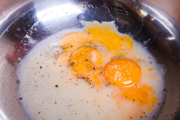 Several yolks with milk in a steel bowl.