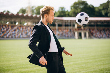 Handsome football player at stadium in business suit