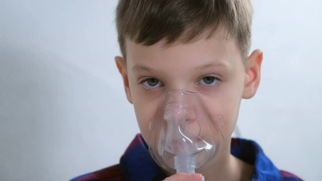 Portrait Of Child Teen Boy Is Breathing In Mask Using Nebulizer For Inhalation Procedure At Home. Fibrosis, Covid-19, Asthma, Copd. Treatment, Cure And Procedure. Using Inhaler For Therapy.