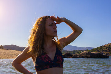 Young woman in bikini with hand on forehead looking into infinity. Summer. Copy space. Selective focus.