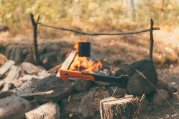 Autumn hiking. The axe in a stump and bowler on the campfire in background. Camping and hiking concept.