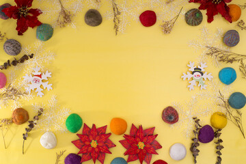 Top view of Christmas background. Decorative yellow background in yellow with colorful balls and dried flowers. 