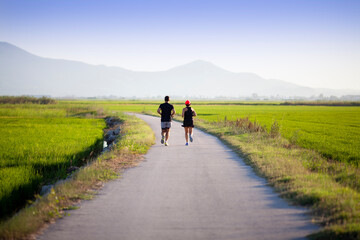 Obraz premium Pareja corriendo al atardecer entre campos de arroz
