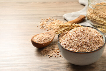 Wheat bran and spikelets on wooden table. Space for text