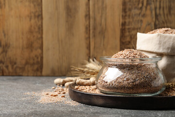 Jar of wheat bran on grey table, space for text