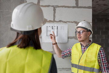 two engineers woman and man in white helmets and yellow safety vests at the construction site...