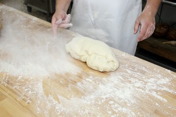 Baker kneading dough on wooden table