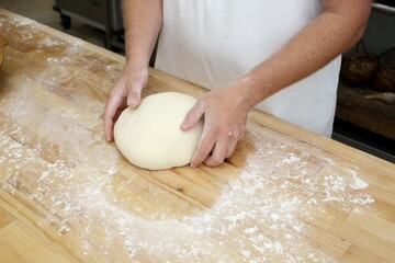 Baker kneading dough on wooden table