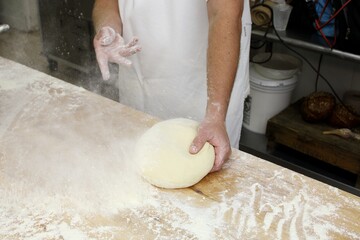 Baker kneading dough on wooden table