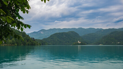 View of beautiful Lake Bled (Blejsko Jezero) with the Pilgrimage Church of the Assumption of Maria on a small island and Bled Castle and Julian Alps at backgroud at summer time.