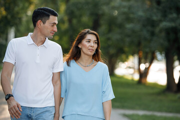 Man and woman walking along a path in a summer park.