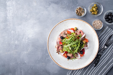 Meat salad with vegetables, ruccola, olives and sunflower seeds. Text space, top view