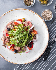 Meat salad with vegetables, ruccola and olives. Top view