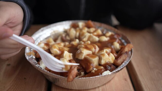 Eating a Poutine Canadian Meal With Cheese and Gravy