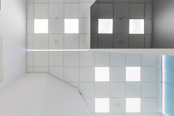 cassette suspended ceiling with square halogen spots lamps and drywall construction in empty room in apartment, clinic, office or house. Stretch ceiling white and complex shape. Looking up view
