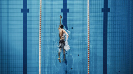 Aerial Top View Male Swimmer Swimming in Swimming Pool. Professional Athlete Training for the...