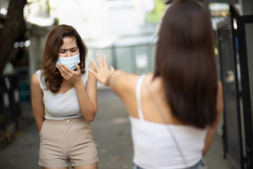 Fearful woman wearing face mask and getting scared off from coughing woman, symptometic infection disease spreading concept