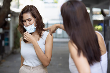 Cautious woman wearing face mask being warning her friend not to remove face mask in public setting