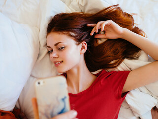 Fototapeta premium pretty woman lying on bed with phone rest chatting at home