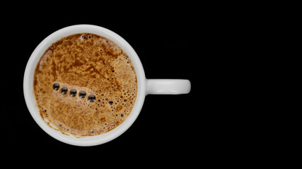 Hot black coffee in white cup on black background, top view
