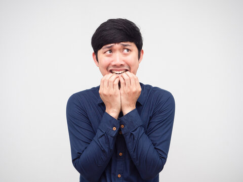 Asian man feeling afraid and bite his hand nail looking up portrait white background - Powered by Adobe