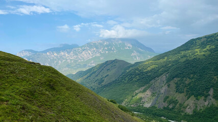 Naklejka premium Amazing landscapes of North Ossetia. Majestic mountains, green hills, blue skies and white clouds.