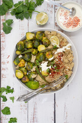 Naklejka premium Quinoa and brussel sprouts on white bowl, wooden table. Feta yogurt sauce. Copy space.