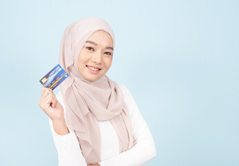 Smiling of young muslim woman in hijab hold in hand credit card. People religious lifestyle concept.