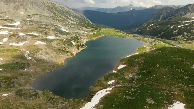 Aerial video of a mountain lake shot from a drone while flying forward with beautiful mountains in the background. Footage was made from a drone above lake Bucura, in Hunedoara county, Romania.