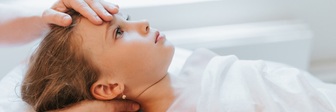 doctor osteopath hands does physiological and emotional therapy for eight year old kid girl. pediatric osteopathy treatment session. alternative medicine. taking care of the child's health. banner